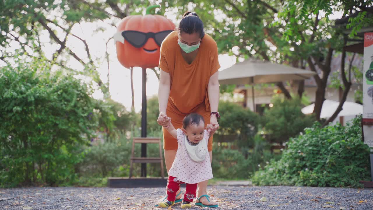 婴儿学习平衡走路蹒跚学步第一步由母亲在后院支持视频素材