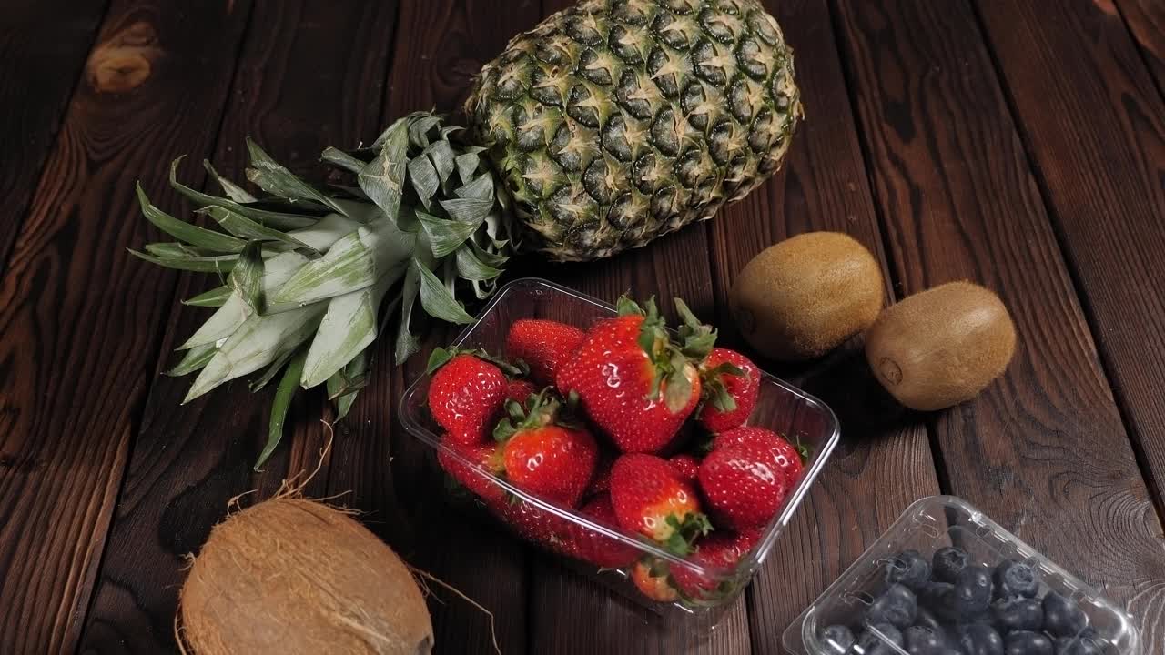 木背景上的新鲜水果特写。鳄梨,草莓,菠萝。视频素材