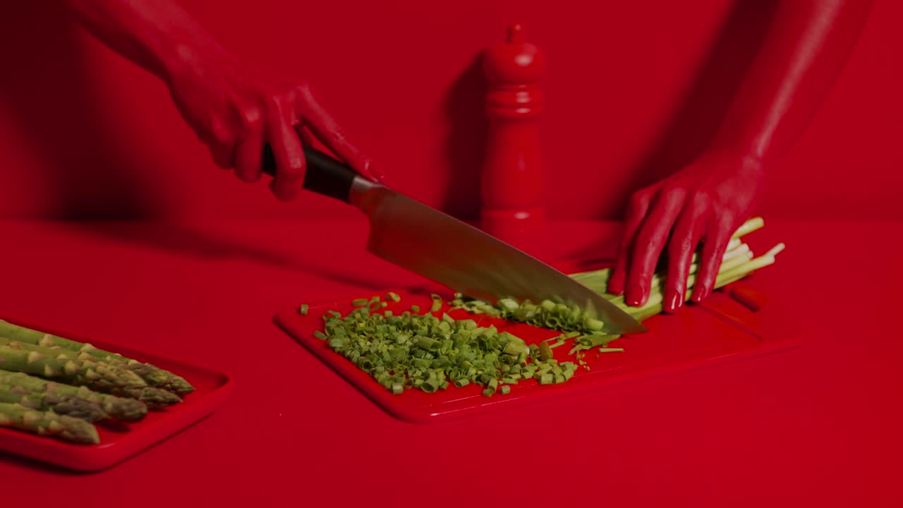 宽阔的镜头，美丽的红女人用刀在船上切韭菜。视频下载