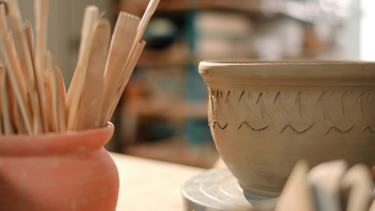 年轻的男陶工在花盆上雕刻图案作装饰视频素材