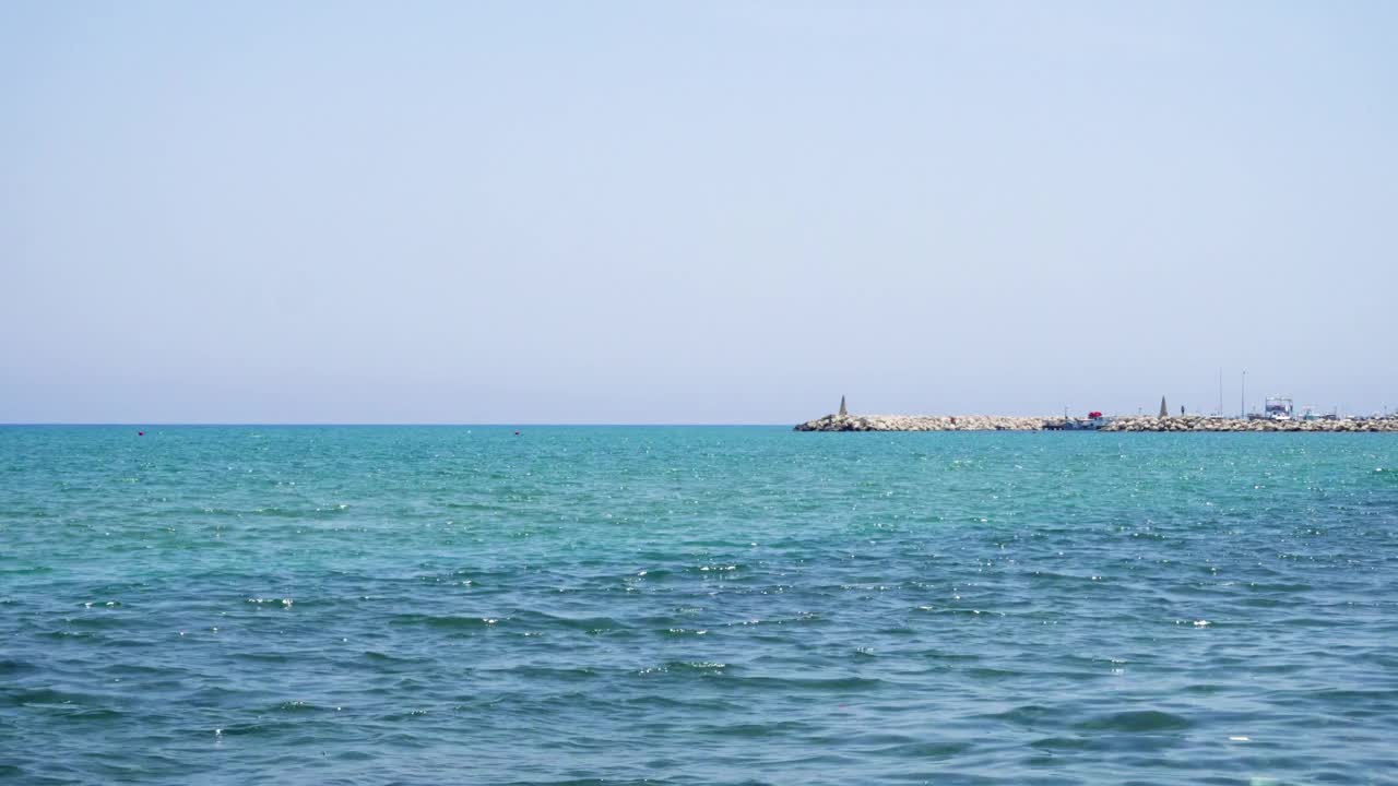 海水拍打着地中海的鹅卵石。全景城市的背景视频下载