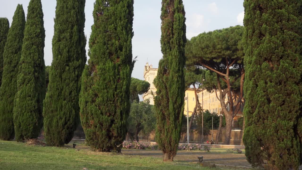 意大利罗马的绿树。摄像机从右向左移动。不认识的人走在背景上视频下载