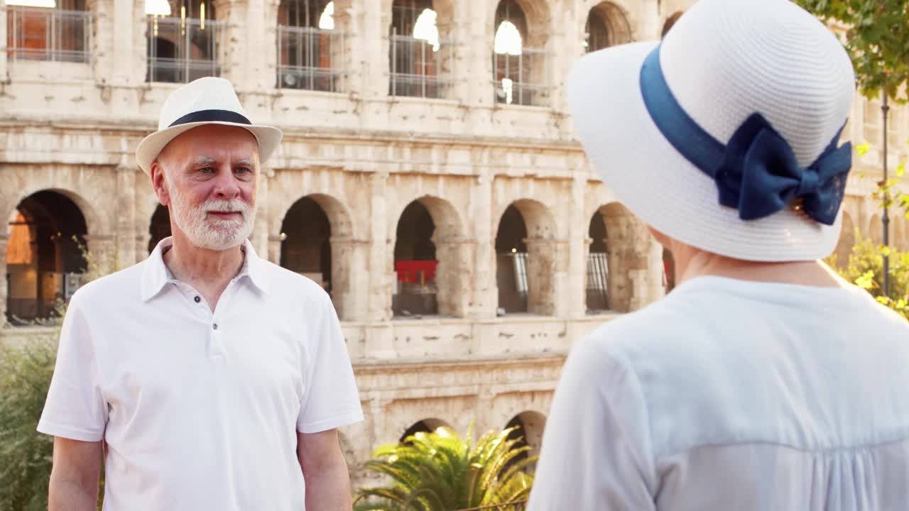 一家老年人在罗马度假。一对老年夫妇在罗马斗兽场附近用手机拍照视频下载