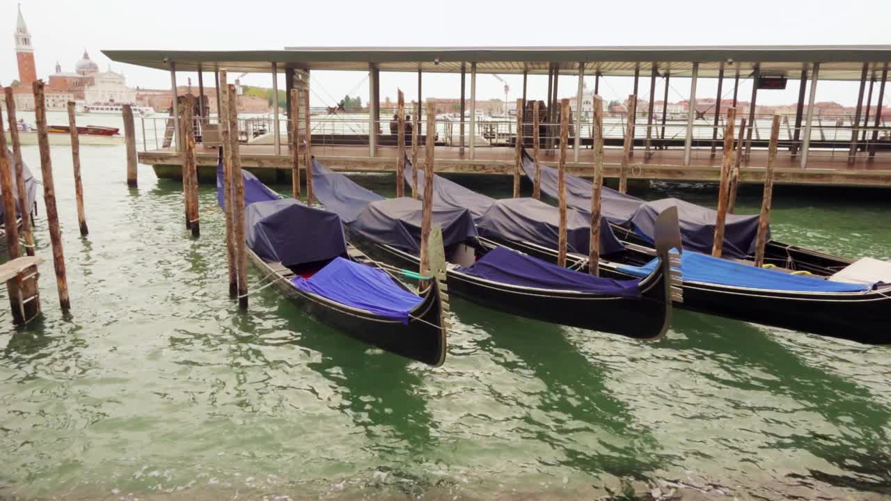 阴沉的一天，意大利威尼斯泻湖上的贡多拉荡秋千。教堂的背景视频下载