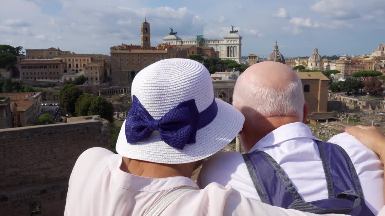 年长的旅行者享受罗马的城市景观。一对在罗马广场附近拥抱的老夫妇环顾四周视频下载