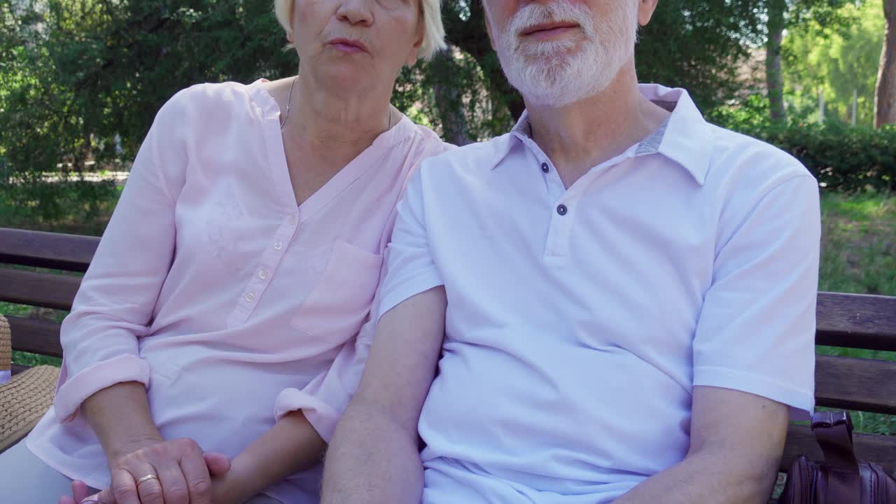 老夫妇坐在公园长椅上轻松聊天。快乐的家庭在户外享受暑假视频下载