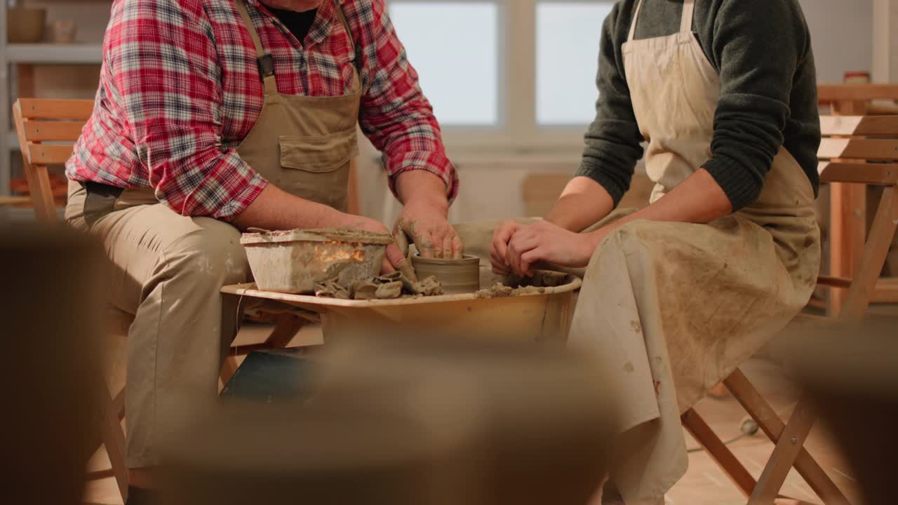 高年级的男陶工向一个男学生展示如何提高纺纱锅的墙壁视频素材