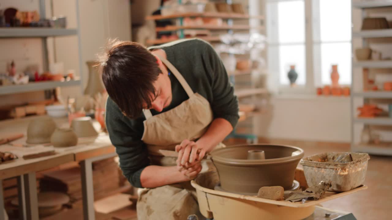 年轻的陶工在陶工轮上做烤盘视频素材