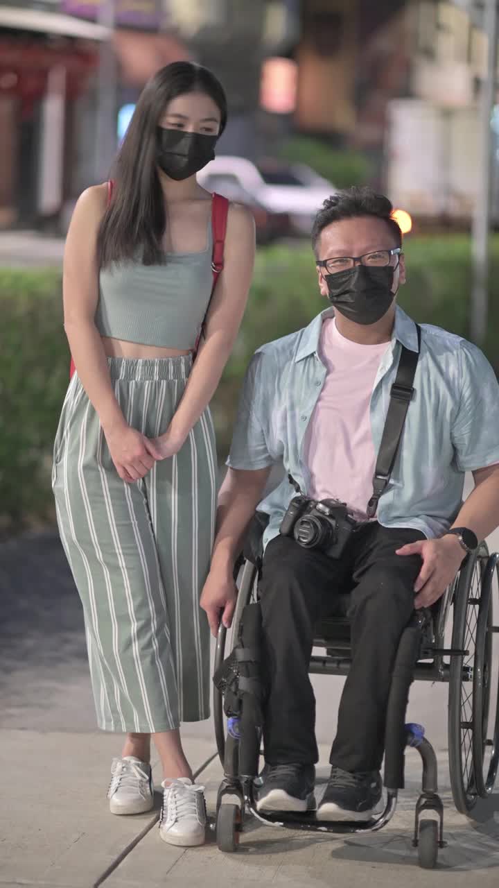 亚洲华人残疾男性与他的女性朋友在吉隆坡晚上肩并肩看相机视频下载