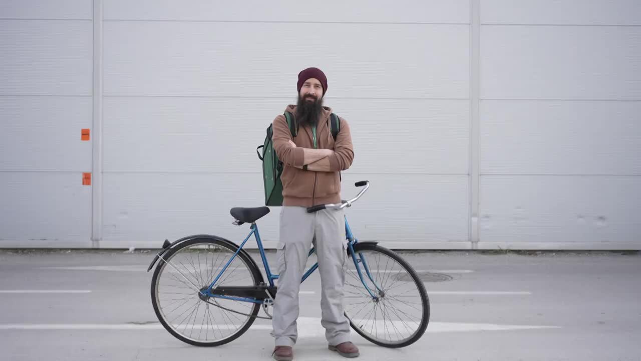自信的男快递员，靠在他的自行车上，准备迎接新的一天的工作视频下载