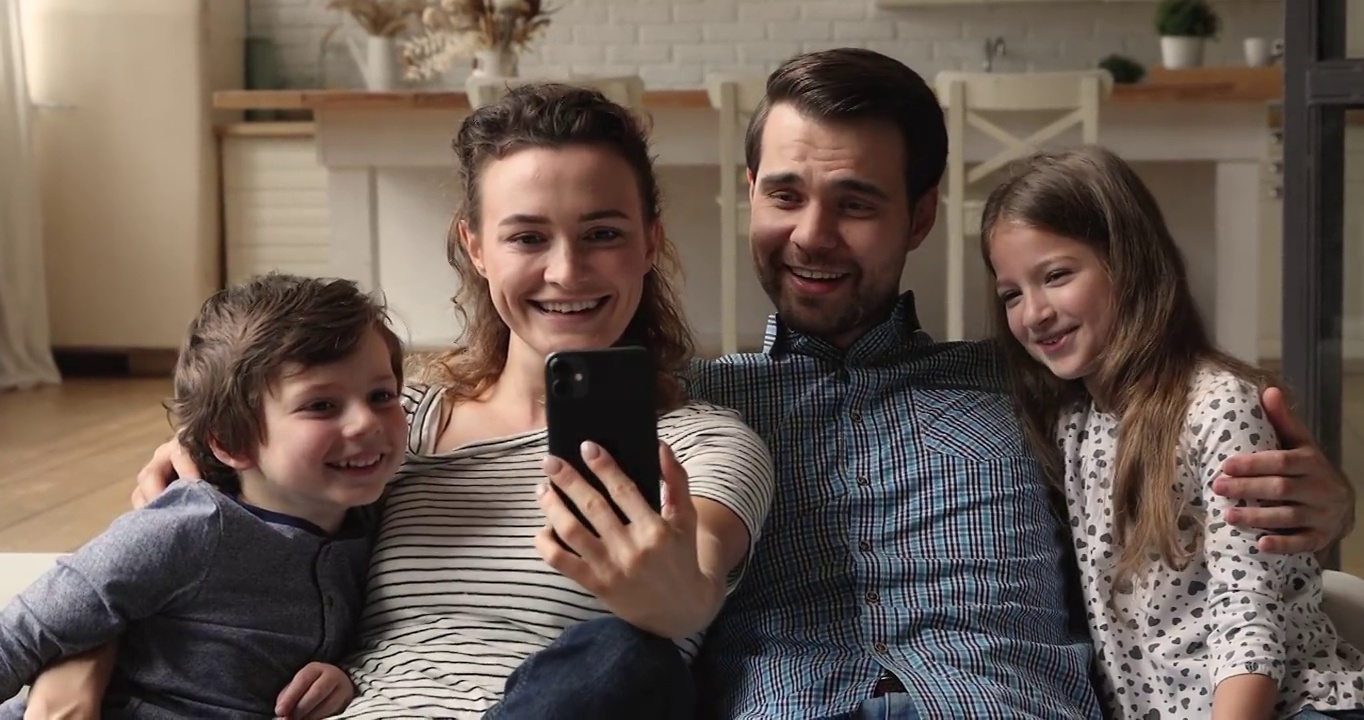 夫妇和孩子们在沙发上玩智能手机视频下载