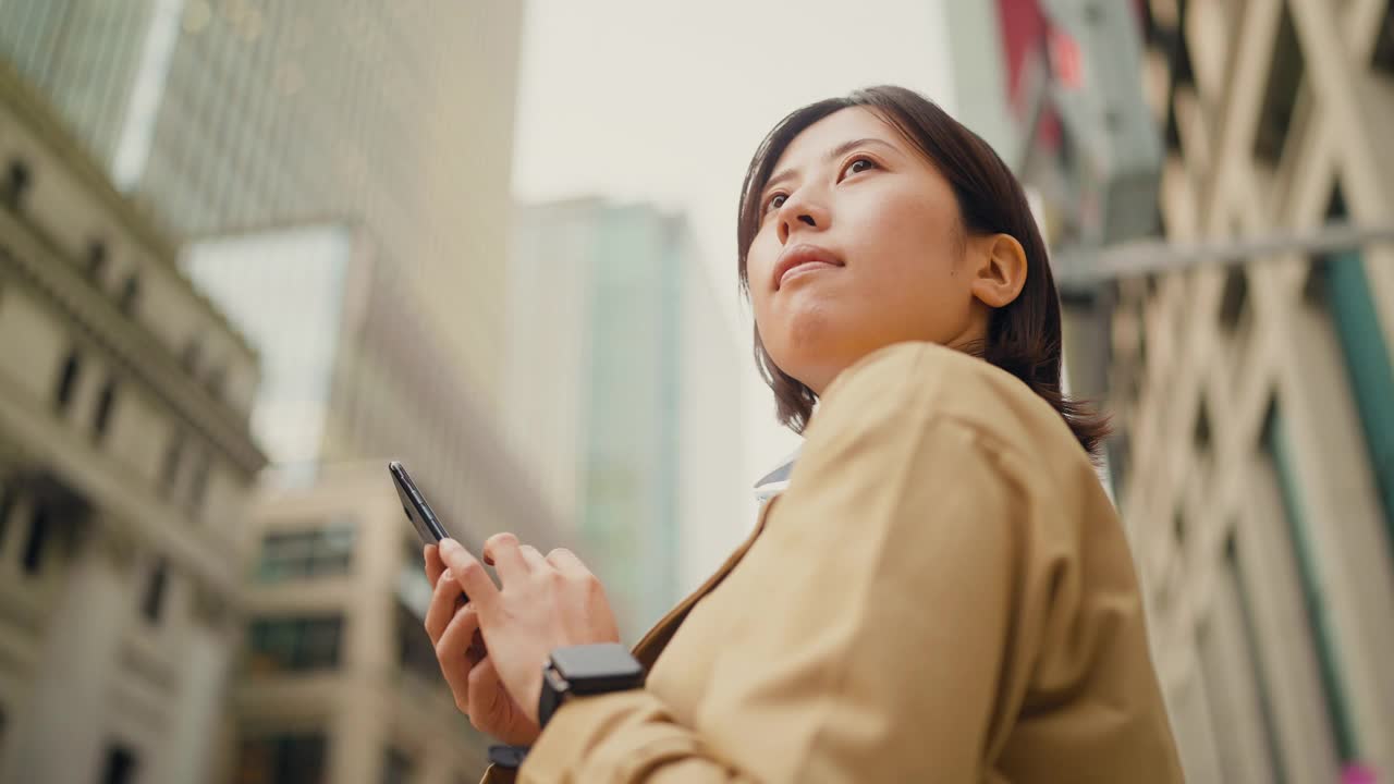 自信的年轻女商人在城市的金融区使用智能手机视频素材