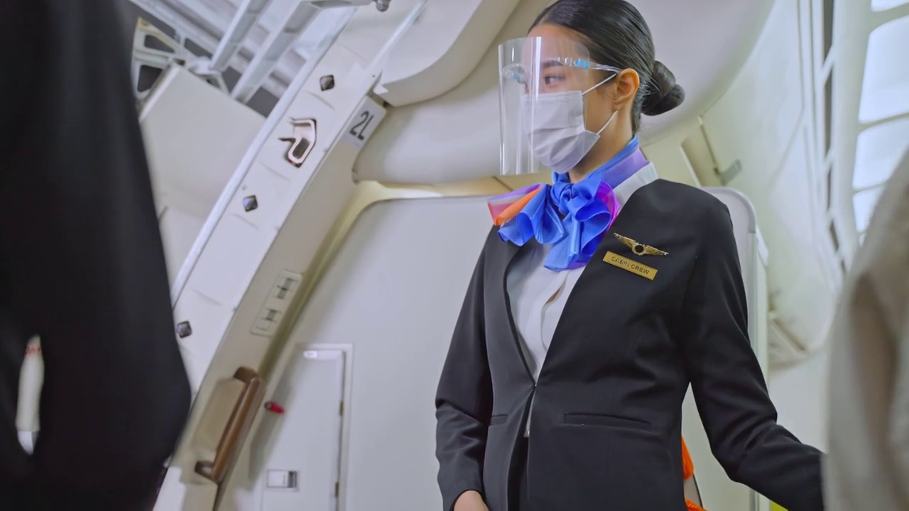 新冠肺炎疫情期间，亚洲空乘人员戴口罩迎接登机和步行的乘客，防止感染新冠肺炎。交通保健概念。视频素材