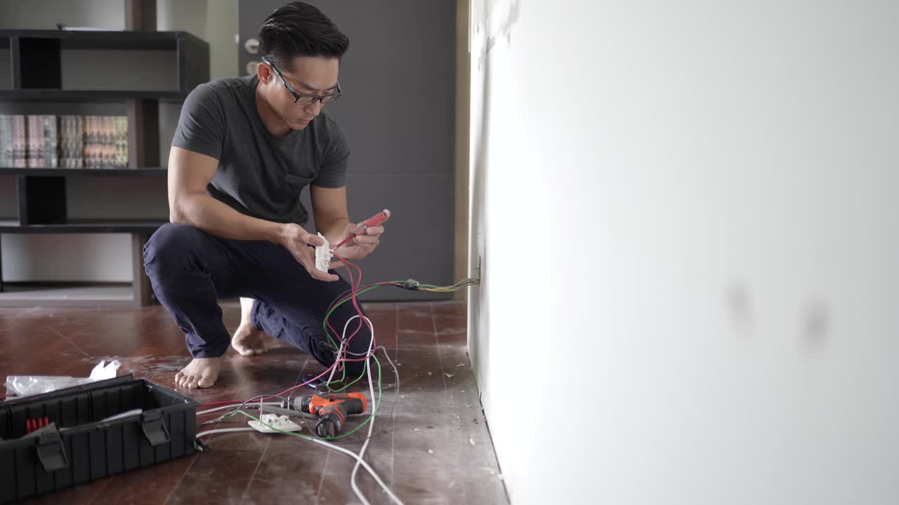 亚洲华人男性电工连接插座到电线。将电线安装到插头上。视频下载