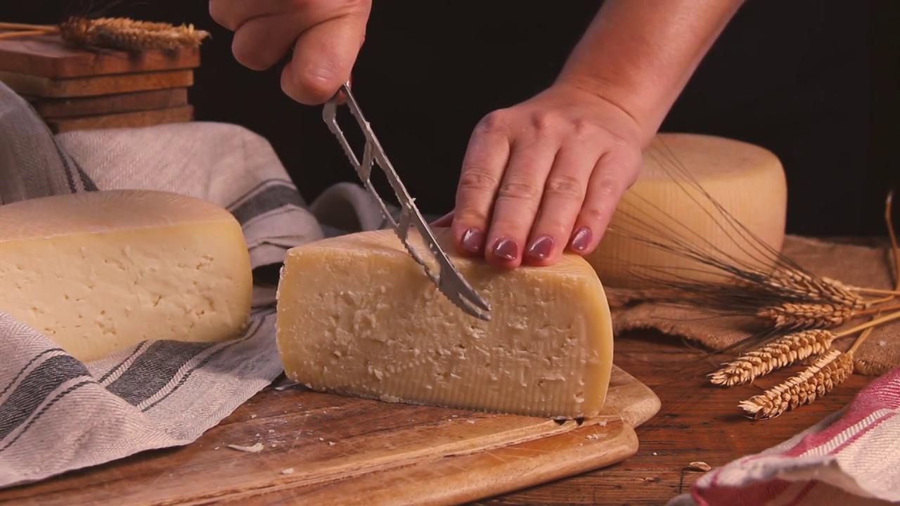 妇女们用奶酪刀在一块木板上切着新鲜的自制奶酪视频下载