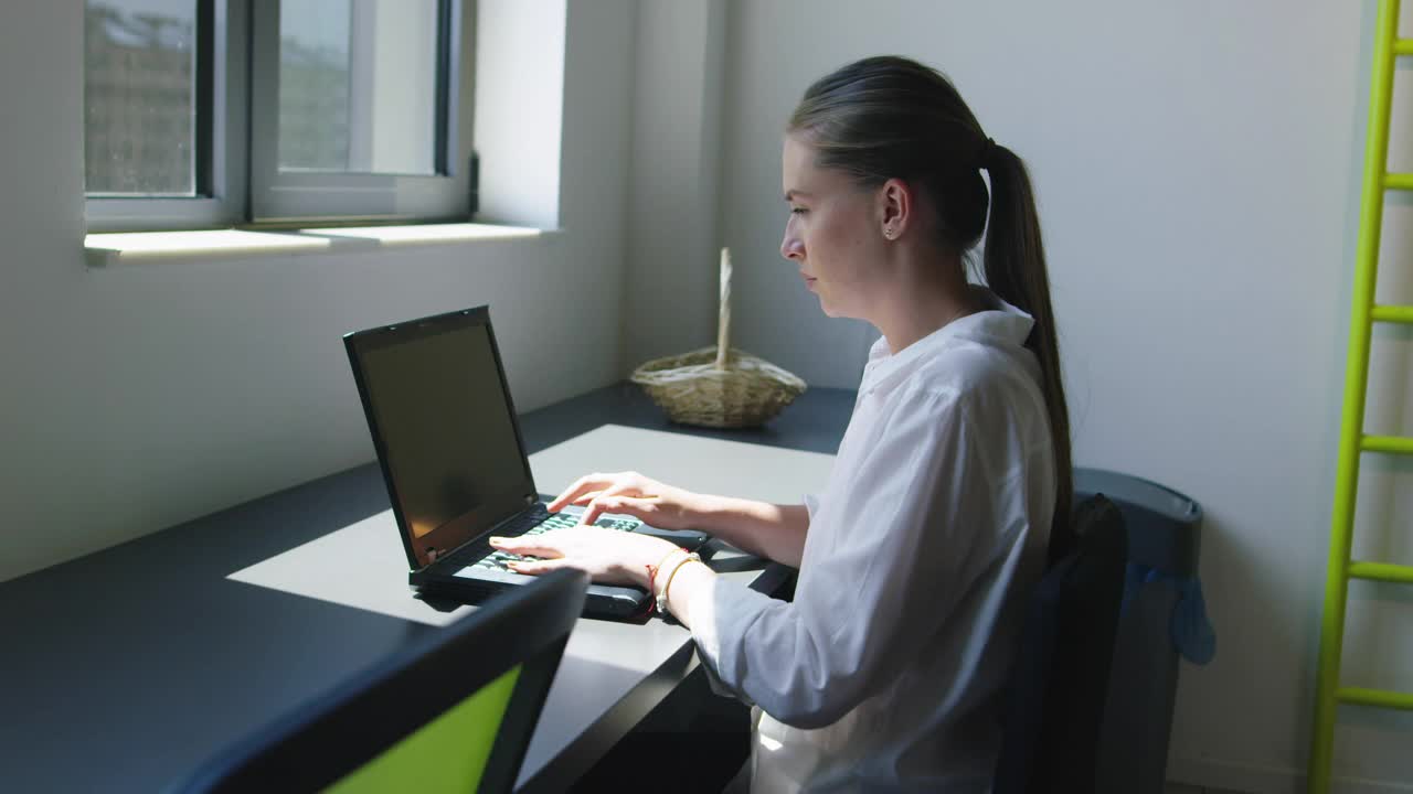 年轻的商业女性坐在初创公司的办公室里使用笔记本电脑视频下载