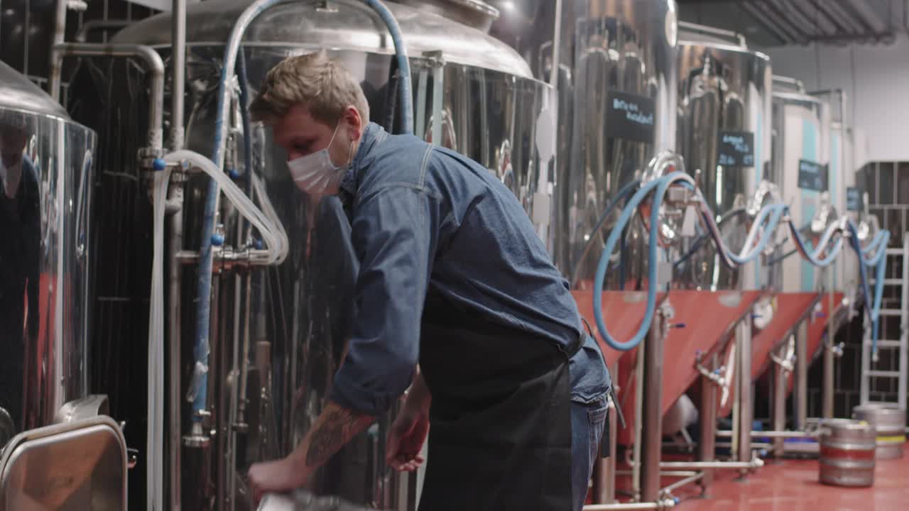 一名男子在啤酒厂搬运沉重的啤酒桶视频下载
