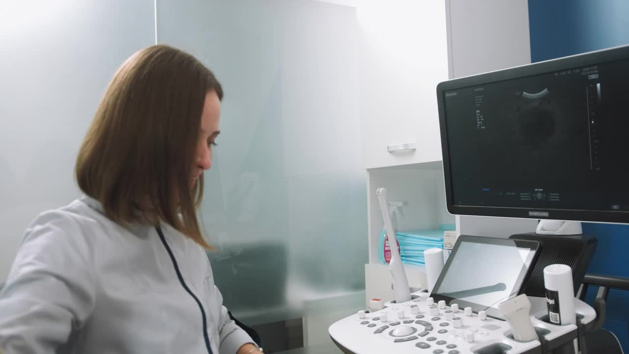 年轻的微笑专业迷人的女医生在做3d超声孕妇的腹部在诊所。孕妇超声波检查。医生把凝胶涂在笼头上视频素材
