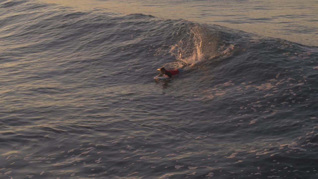 航空跟踪拍摄的远距离男子在日落海浪上冲浪/圣布拉斯，拉利伯塔德，萨尔瓦多视频下载