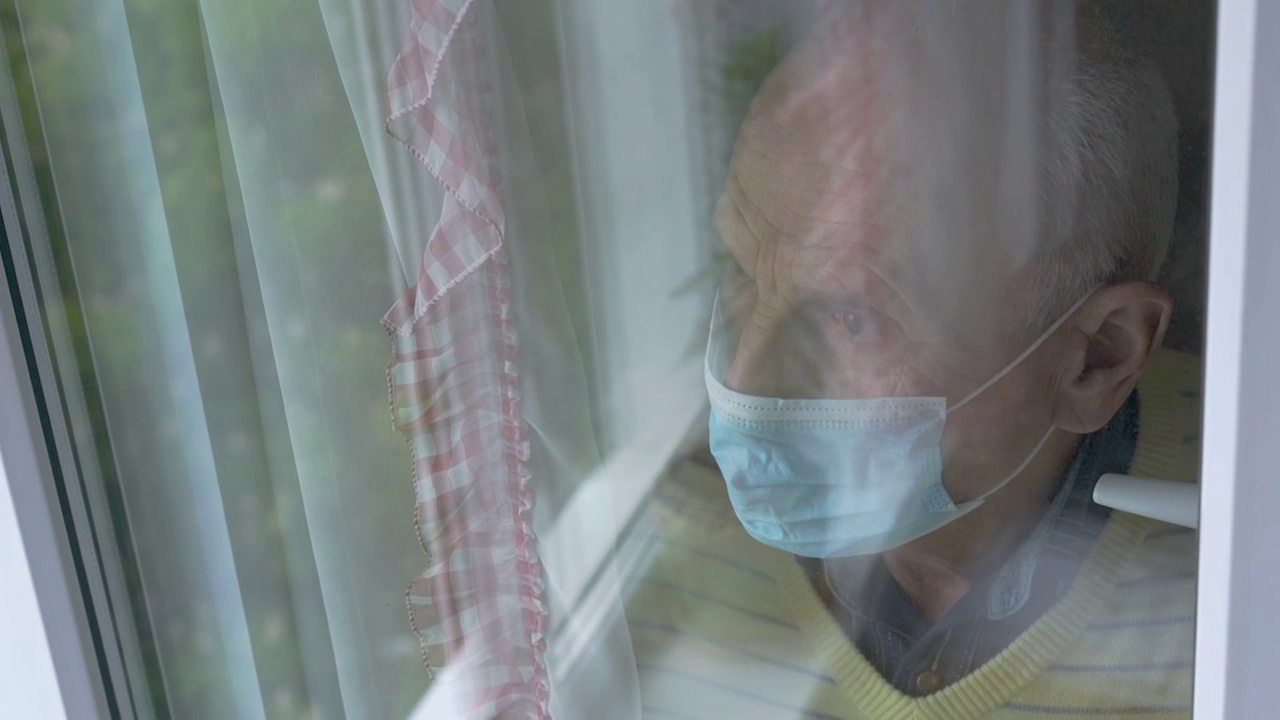 沮丧的老人在面具反射在窗户上方的视图视频素材