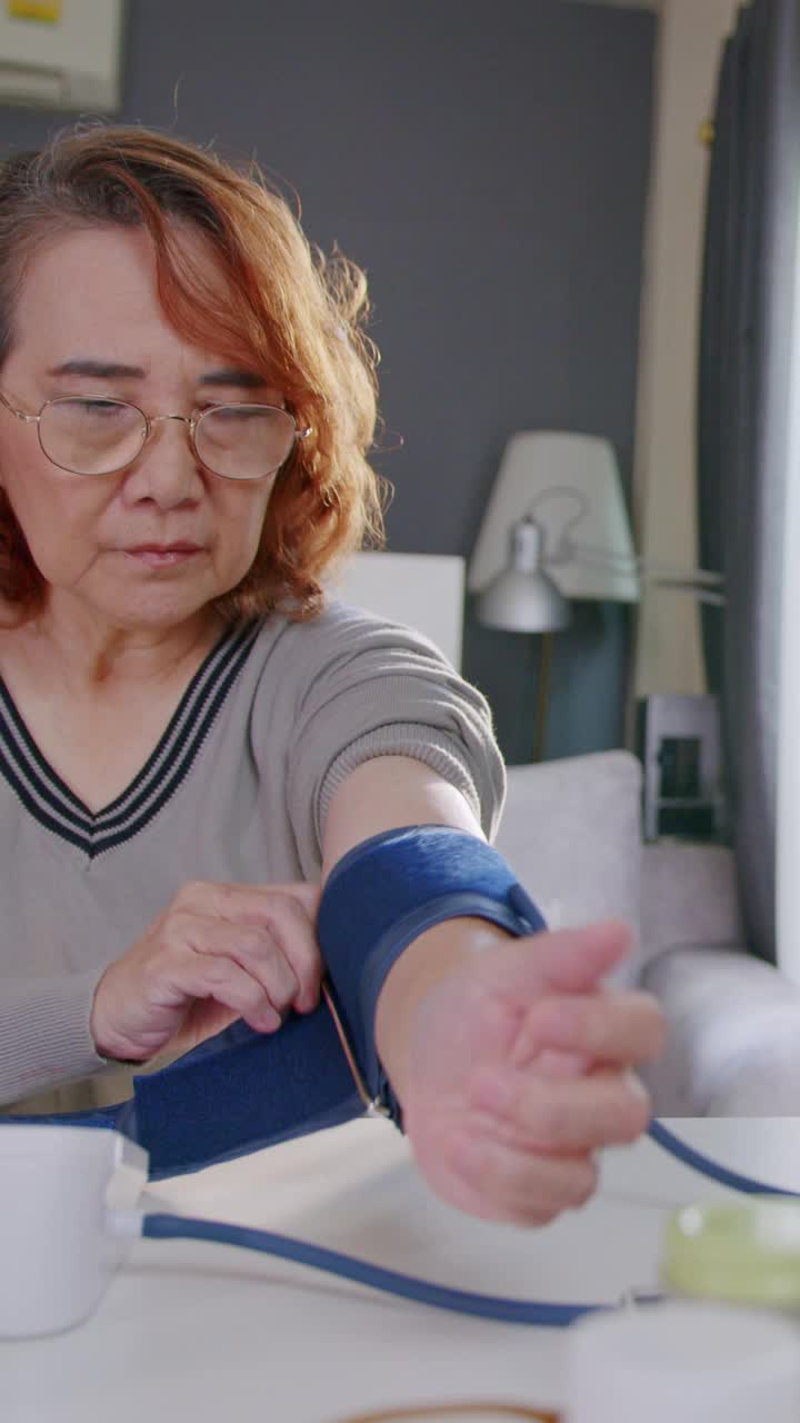 一位老妇人在家里用监测仪测量自己的血压。视频素材