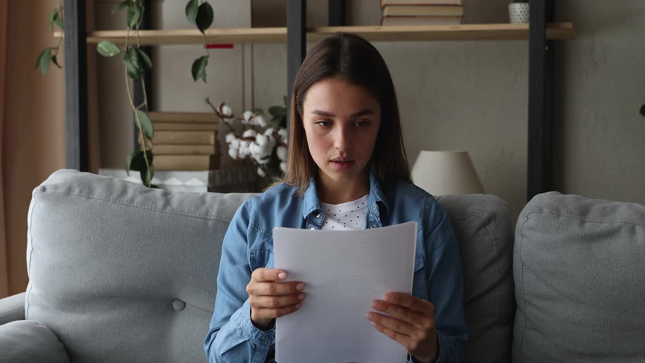一个女人坐在沙发上读着一封信，里面有个坏消息视频素材