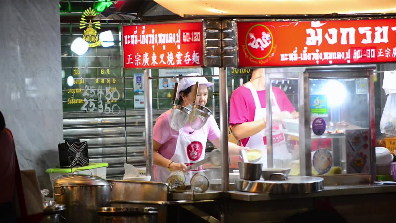 在曼谷耀华路的一个摊位上，一个街头小吃小贩正在做饭视频素材