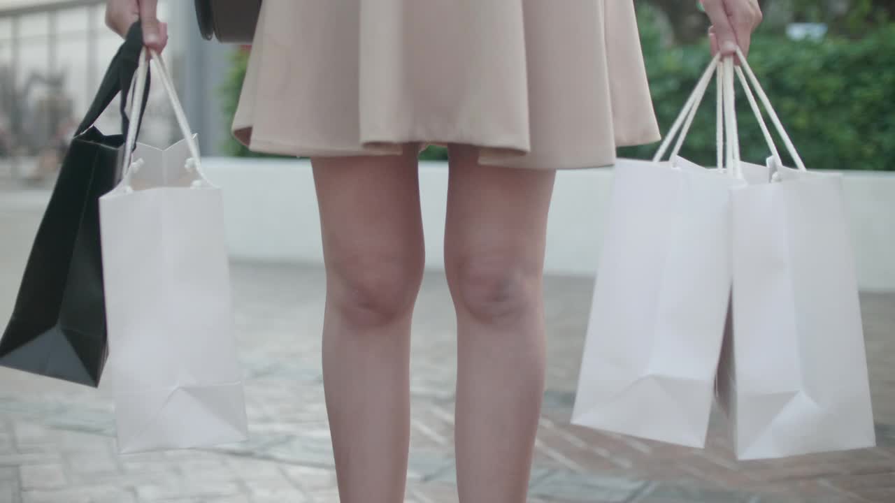 快乐的亚洲女人展示她的购物袋在她的手视频素材