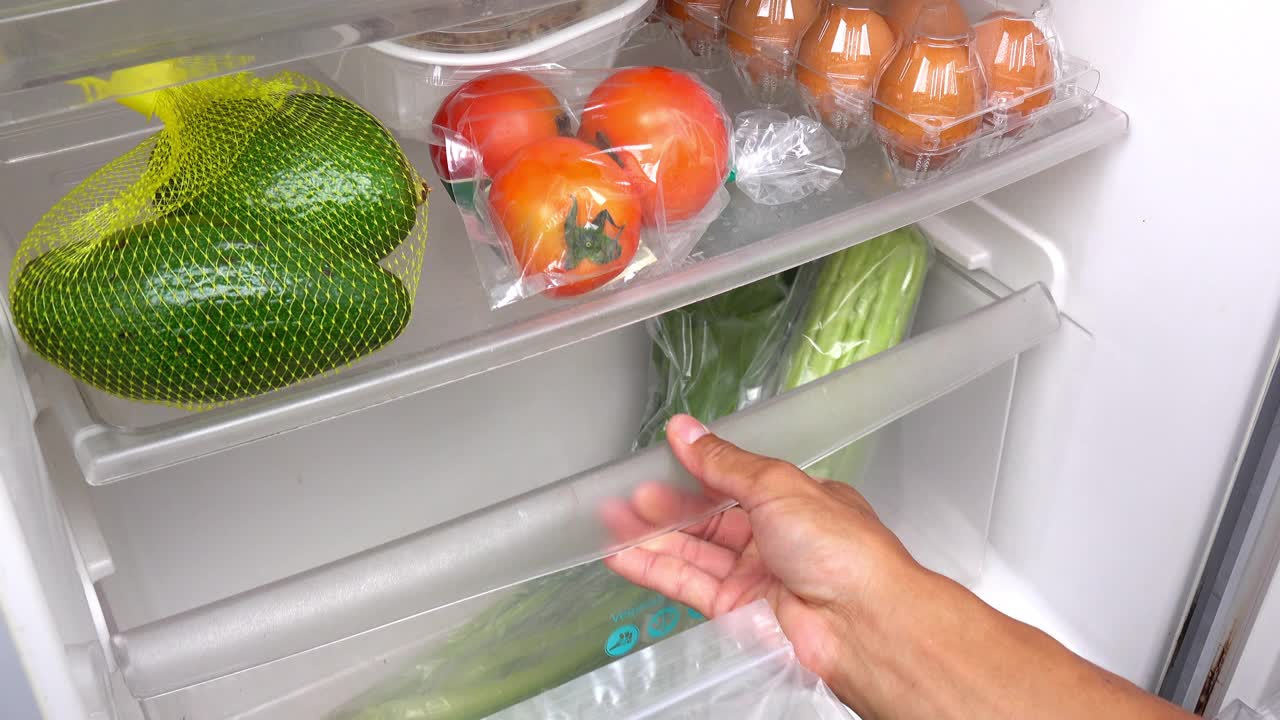 一个男人正在把蔬菜放进冰箱。视频下载