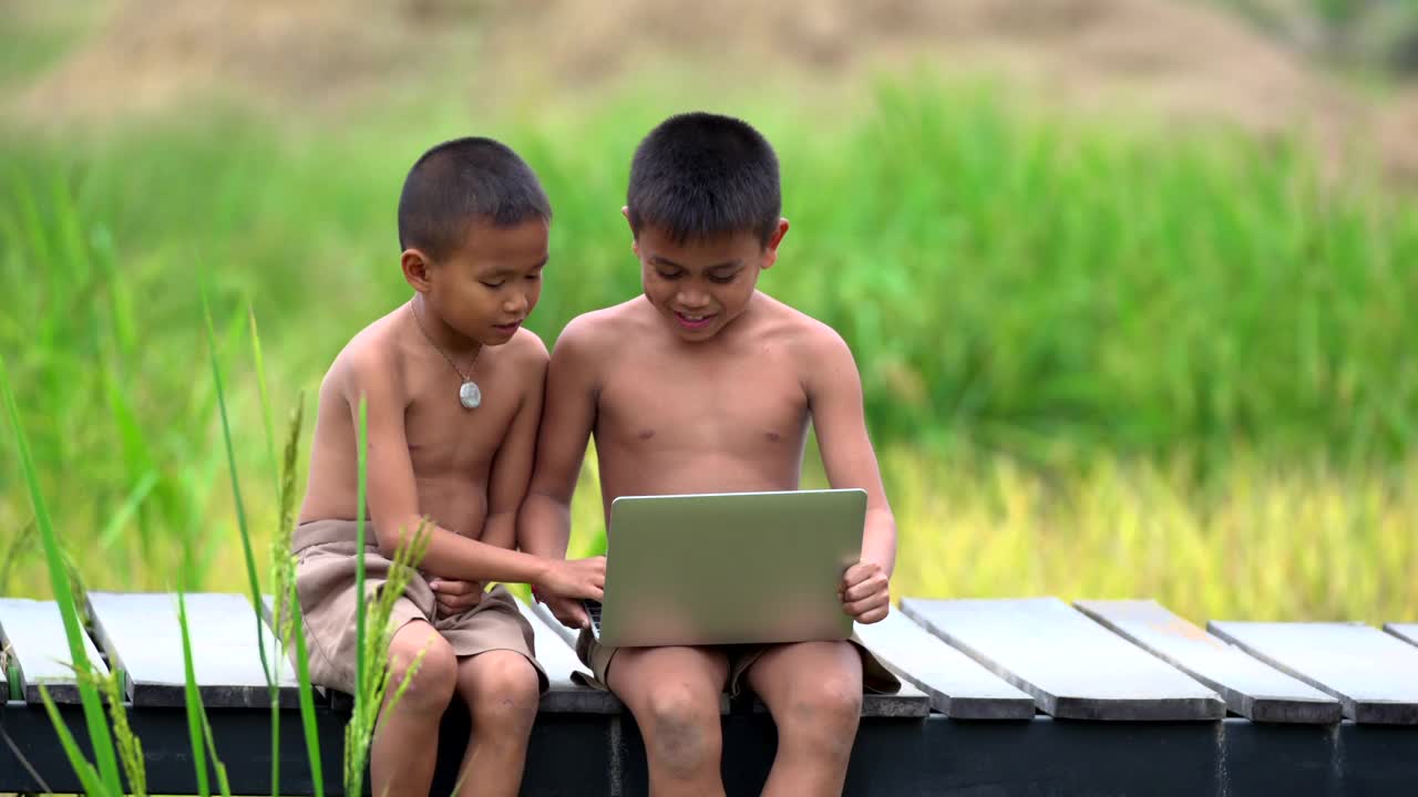 两个农村男孩愉快地玩着笔记本视频素材