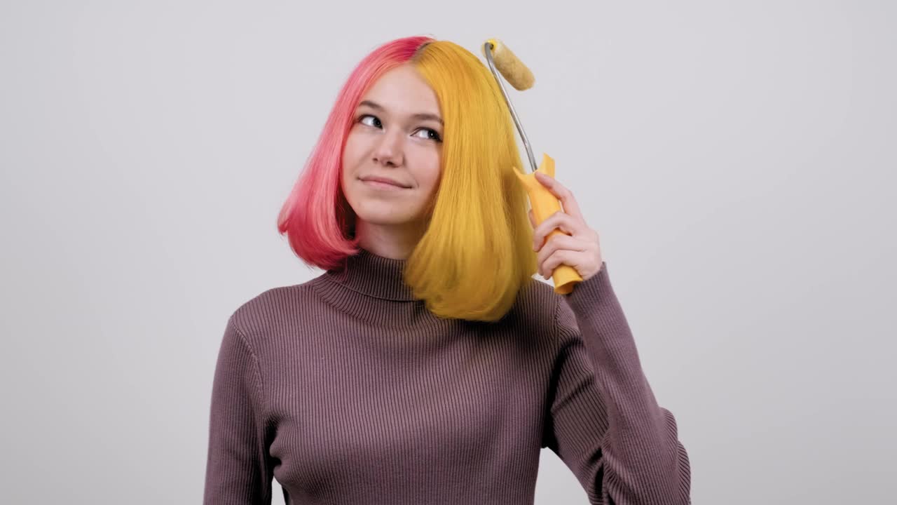 美丽的少女用建筑滚筒染她的头发，少女用时尚的颜色的发型视频下载