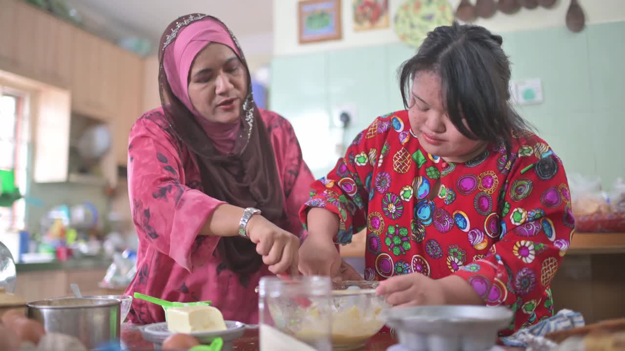 马来西亚母亲和她患有唐氏综合症的女儿在厨房里做传统的马来甜点视频下载