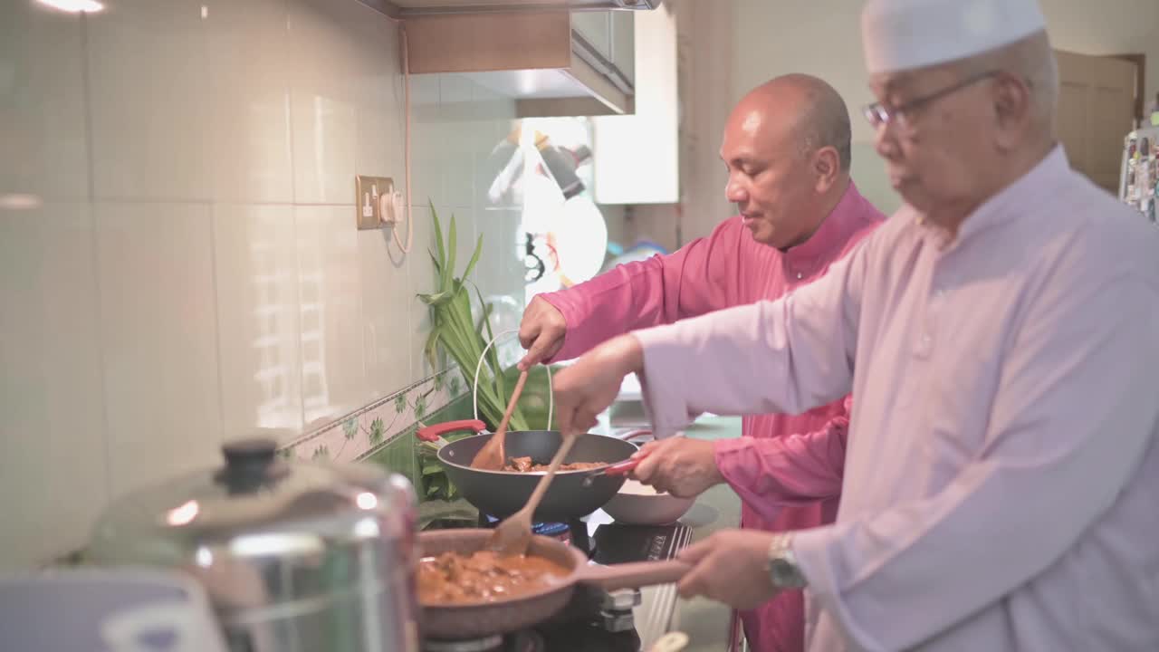 马来家族的祖父和父亲在厨房里并排烹饪传统食物咖喱，准备开斋的家庭团圆饭视频下载