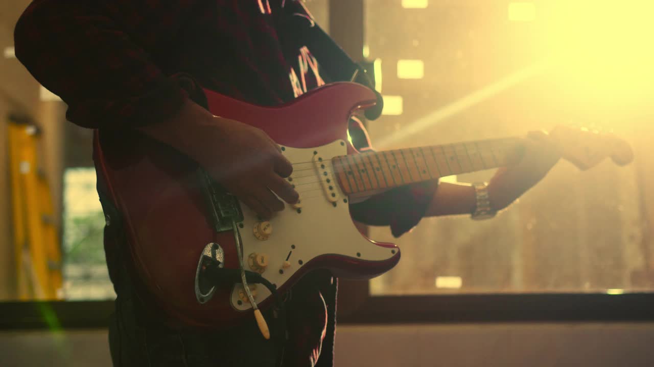 近手的音乐家弹奏电吉他的歌曲与音乐与灯光闪耀的背景视频素材