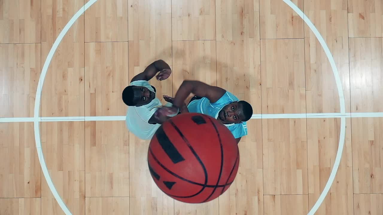 俯视图的体育馆有两个非洲裔美国运动员练习篮球视频下载