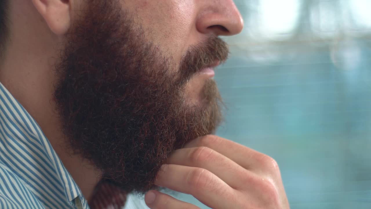大胡子男子摸着胡子思考的特写镜头。视频下载