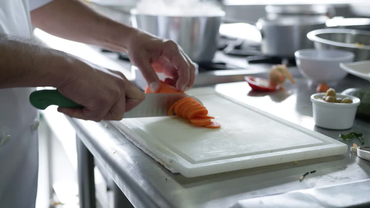 近距离拍摄一位面目全非的厨师在餐厅厨房切胡萝卜视频素材