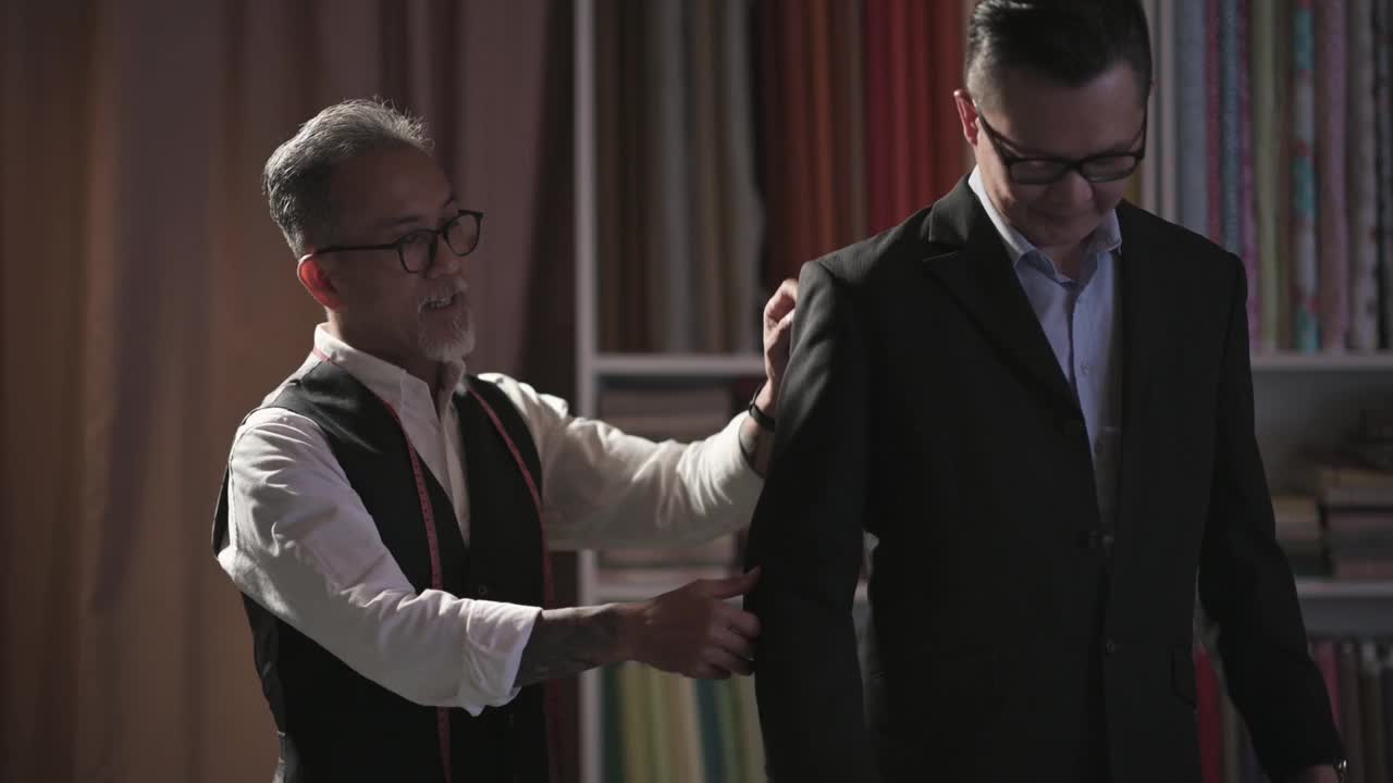 亚洲华人成熟男子裁缝与脸胡茬帮助他的客户试穿新的定制西装视频下载