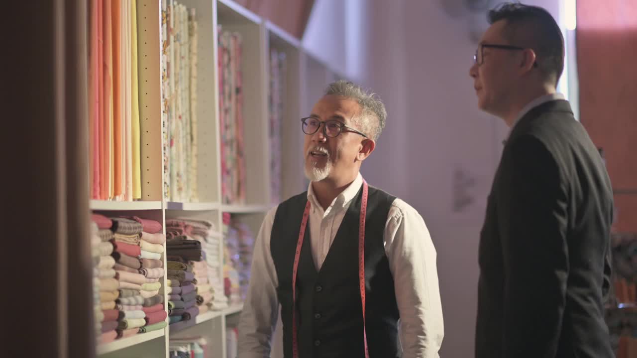 Atelier亚洲华人成熟男子裁缝展示他的客户的面料定制西服视频下载