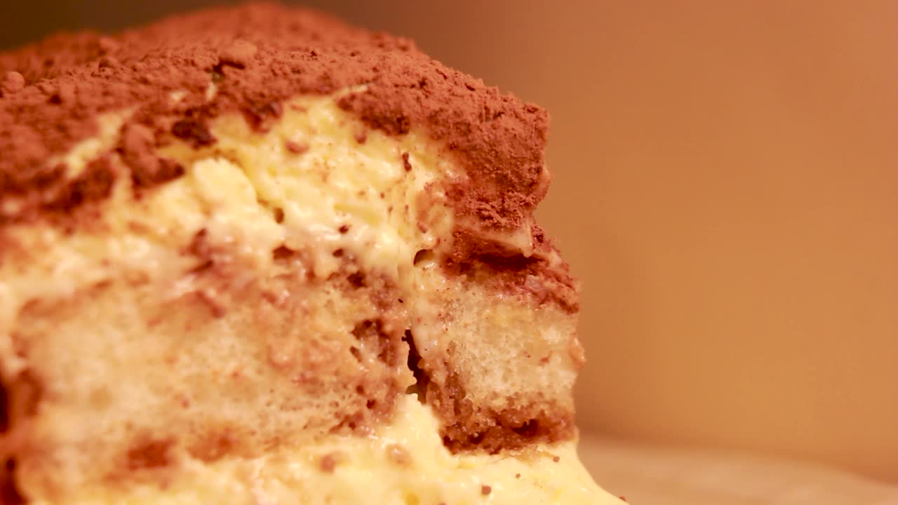 极端选择性聚焦微距提拉米苏甜点蛋糕在普通的背景和一个用过的勺子取一片。视频下载