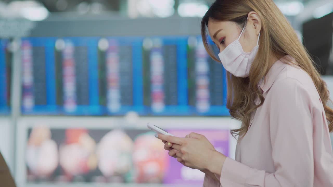 亚洲妇女在机场乘坐公共交通工具时戴着白色口罩使用手机视频素材