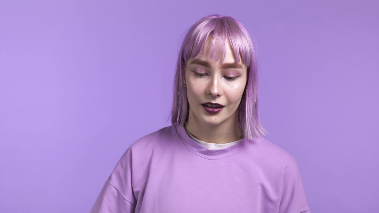 漂亮的女人显示拇指像标志在紫罗兰工作室背景。积极的年轻女孩与染成紫色的头发微笑的相机。赢家。成功。肢体语言。视频下载