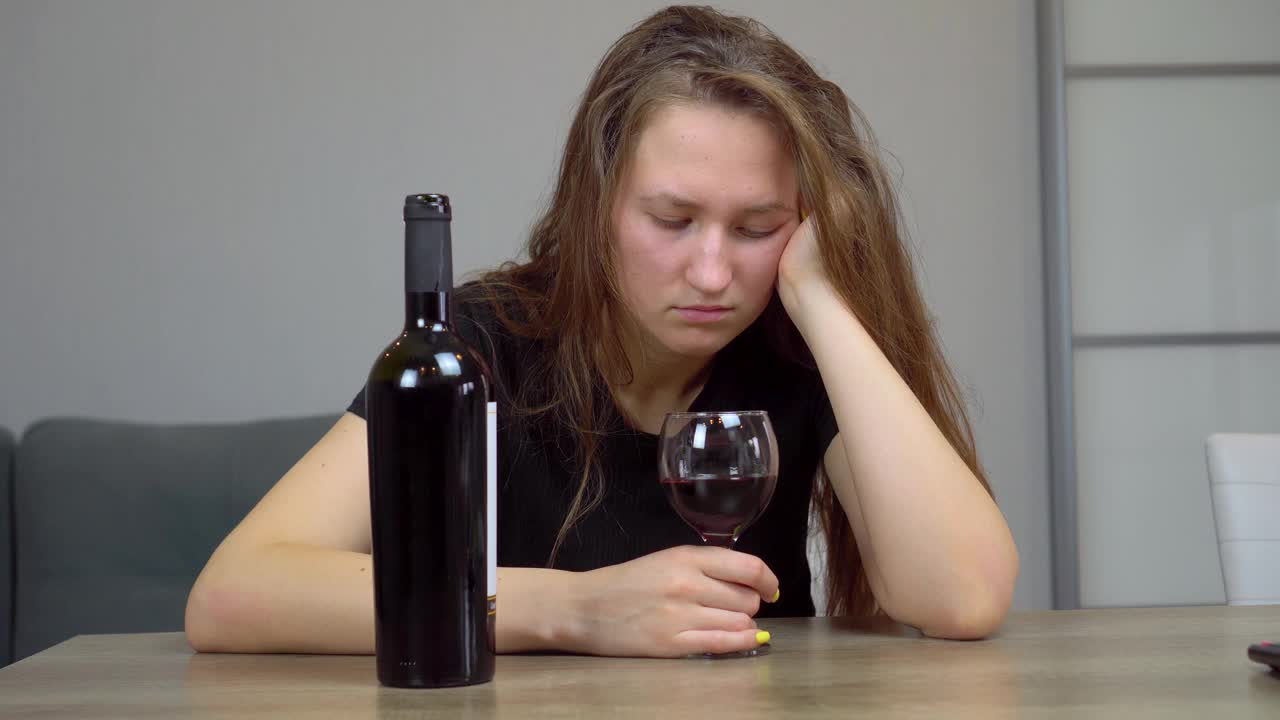 女人是一个悲痛欲绝的酒鬼，坐在家里的沙发上喝红酒视频下载