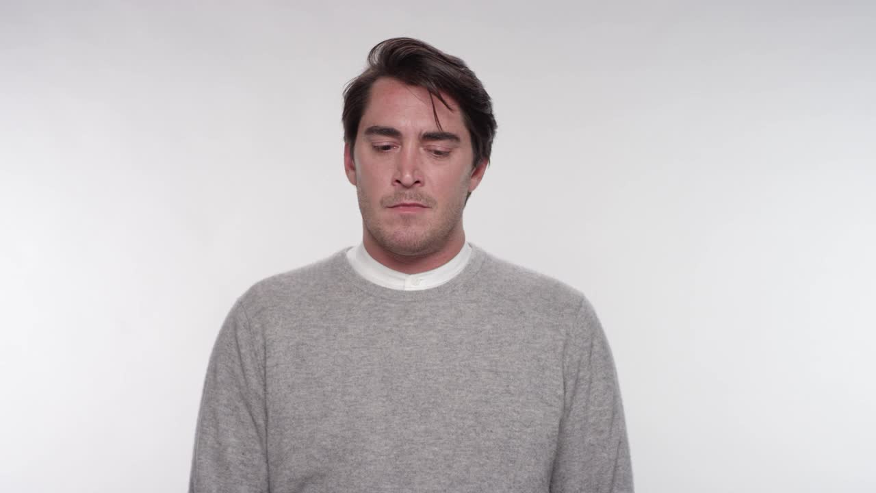 一个疲惫、愤怒、沮丧的男人的肖像在一个白色的摄影棚背景下视频下载