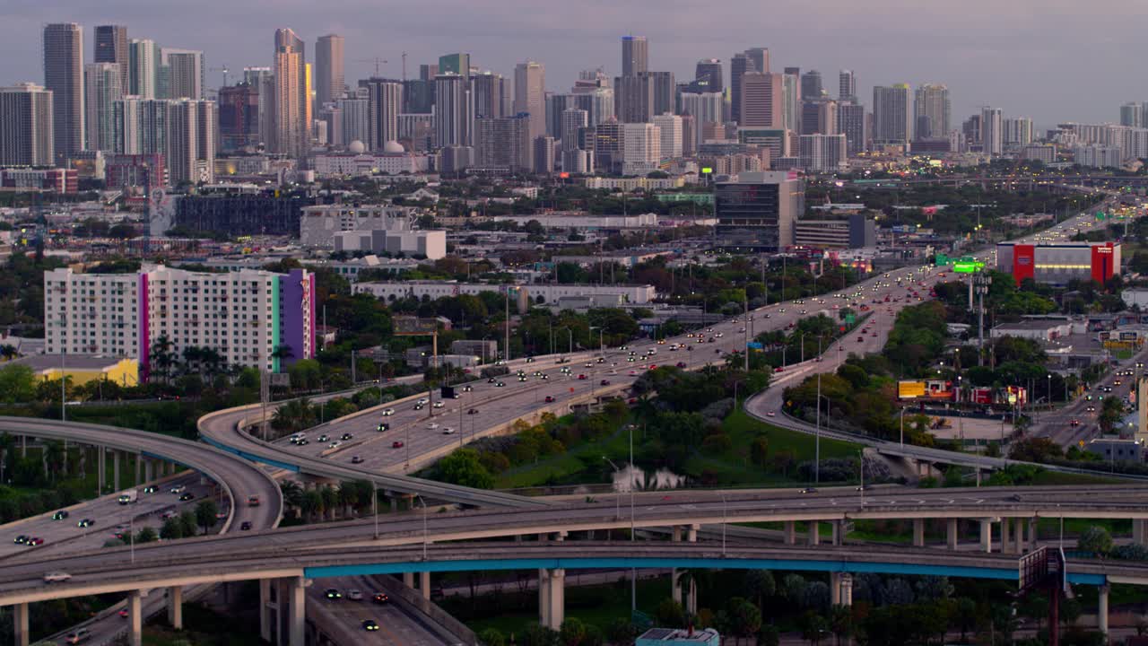 鸟瞰图迈阿密设计区和遥远的迈阿密市中心上空的大高架枢纽在北迈阿密，佛罗里达州，在晚上。无人机拍摄的b-roll镜头和平移摄像机的运动。视频下载