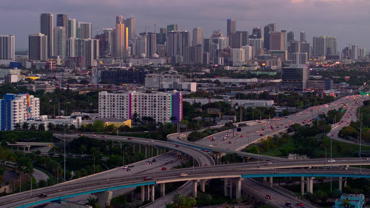 鸟瞰图迈阿密设计区和遥远的迈阿密市中心上空的大高架枢纽在北迈阿密，佛罗里达州，在晚上。无人机拍摄的b-roll镜头和下降的摄像机动作。视频下载