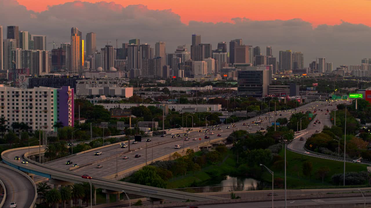日落时分，从美国佛罗里达州北迈阿密的高架十字路口，以及繁忙的95号州际公路，眺望迈阿密市中心。用无人机拍摄的后向镜头。视频下载