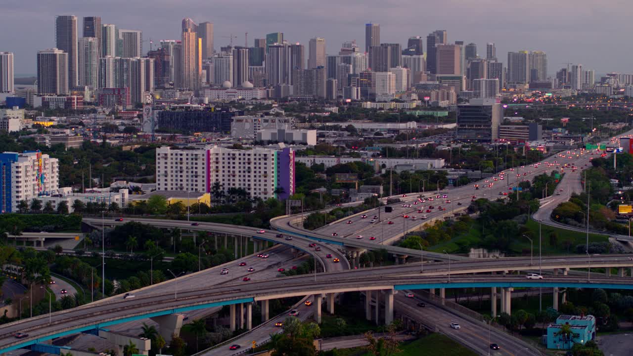 鸟瞰图迈阿密设计区和遥远的迈阿密市中心上空的大高架枢纽在北迈阿密，佛罗里达州，在晚上。无人机拍摄的b-roll镜头和静态摄像机。视频下载
