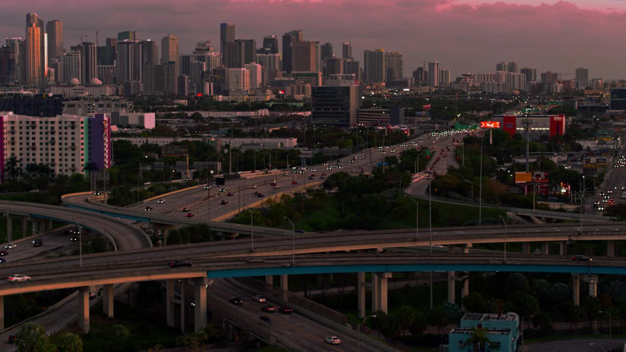 日落时分，从美国佛罗里达州北迈阿密的高架十字路口，以及繁忙的95号州际公路，眺望迈阿密市中心。无人机制作的b-roll镜头与平移摄像机运动。视频下载