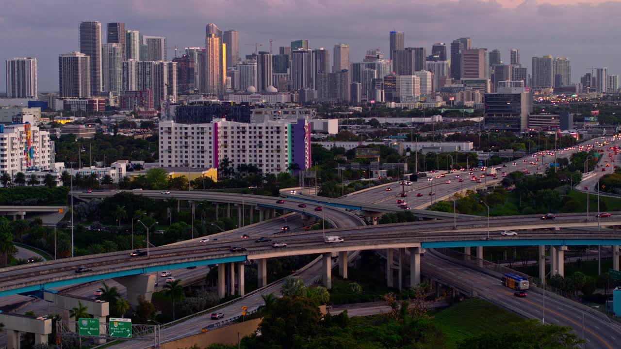 鸟瞰图迈阿密设计区和遥远的迈阿密市中心上空的大高架枢纽在北迈阿密，佛罗里达州，在晚上。无人机拍摄的b-roll镜头和前向摄像机运动。视频下载